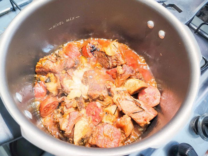 Uma panela de pressão contendo carnes cozidas com caldo.