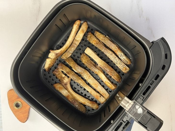 Uma airfryer com pedaços de costela de tambaqui fritando.