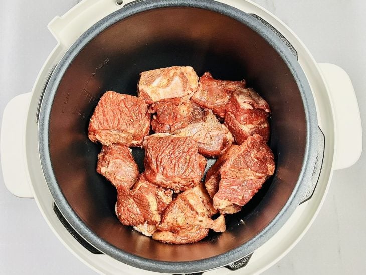 Panela elétrica com azeite, cebola e pedaços de costela.