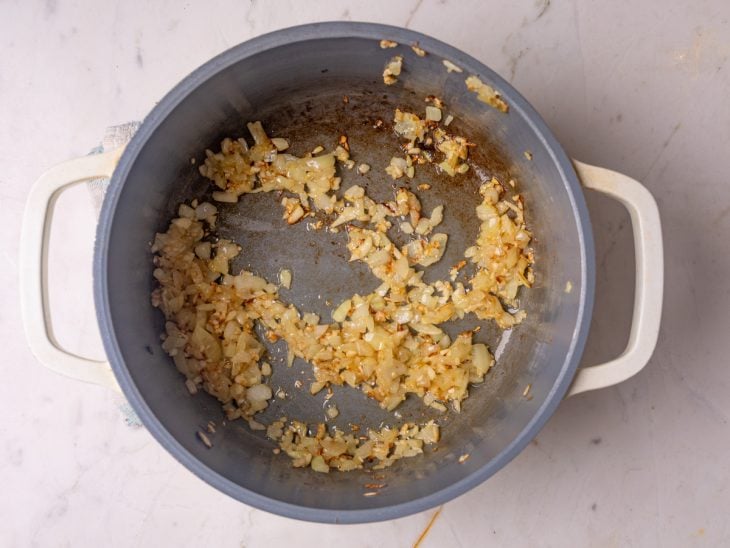 Uma panela com alho e cebola refogando.