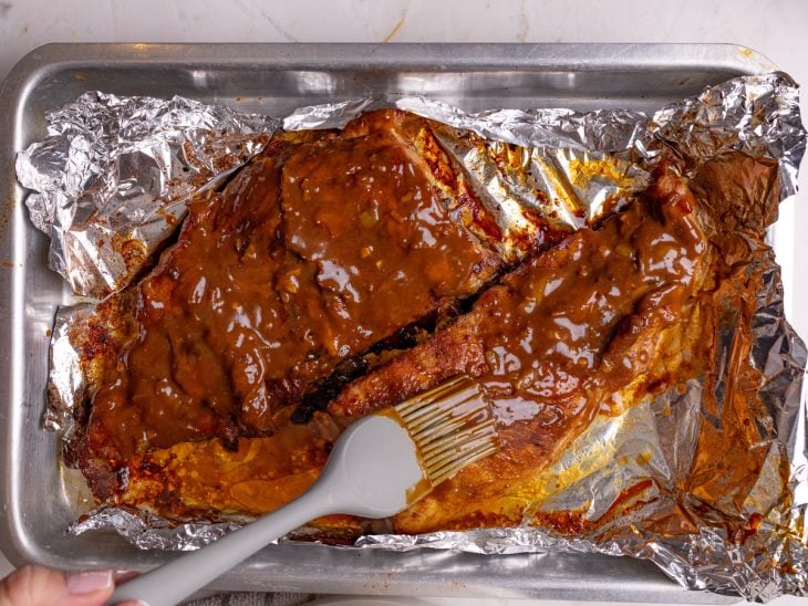 Molho barbecue sendo pincelado nas costelinhas.