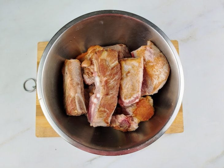 Costelinhas de porco douradas e reservadas em um recipiente.