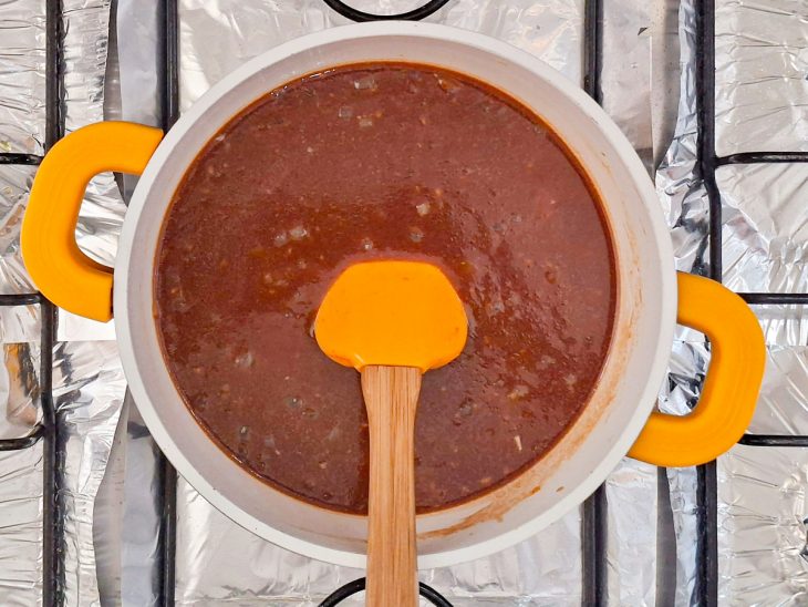 Ingredientes líquidos do molho sendo adicionados à panela e misturados.