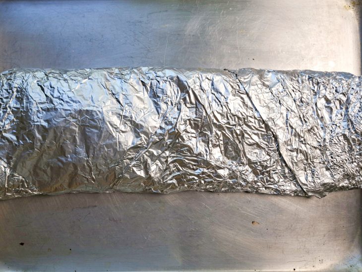 Peça de costelinha embrulhada com papel-alumínio, pronta para assar.