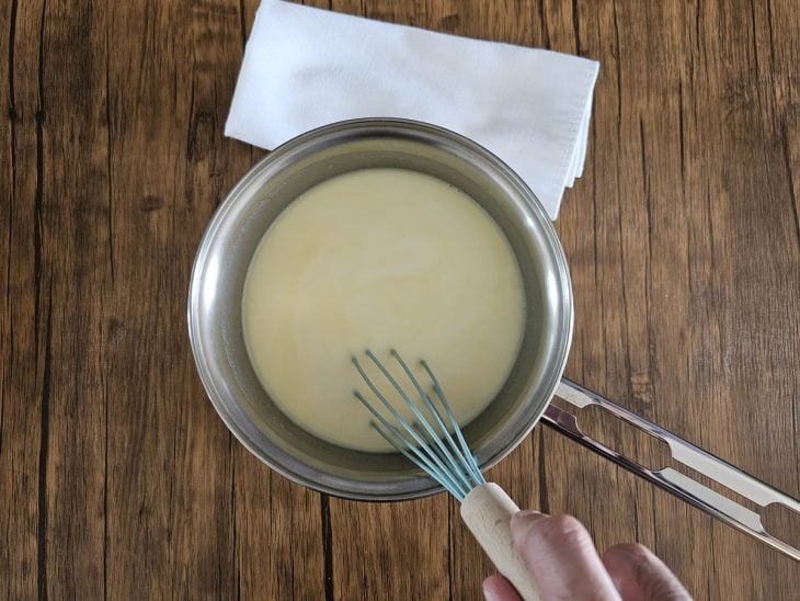 Panela com fouet misturando a mistura de manteiga, farinha e leite.