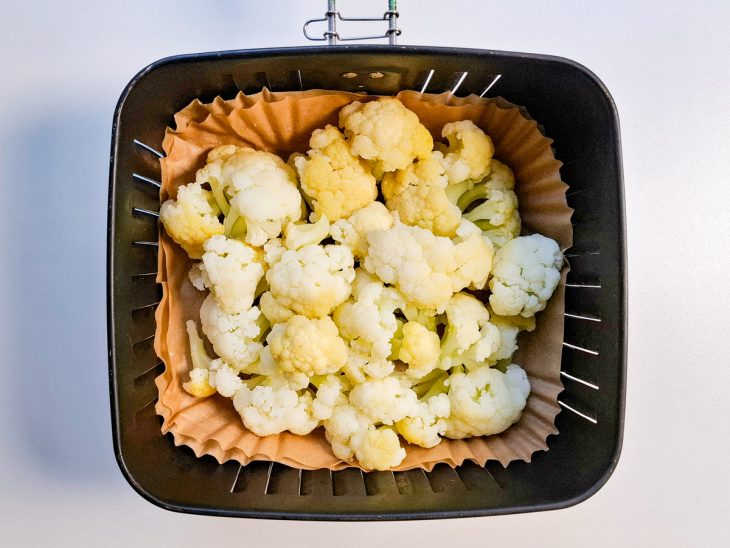Floretes colocados no cesto da air fryer forrado por papel manteiga.
