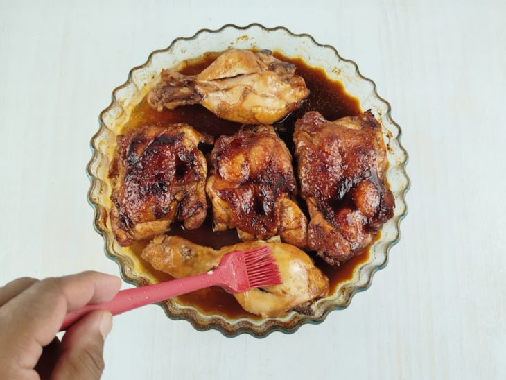 Frango assado parcialmente sendo pincelado com o molho.