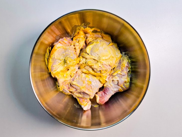 Numa tigela, frango temperado com sal, mostarda, maionese e vinagre.