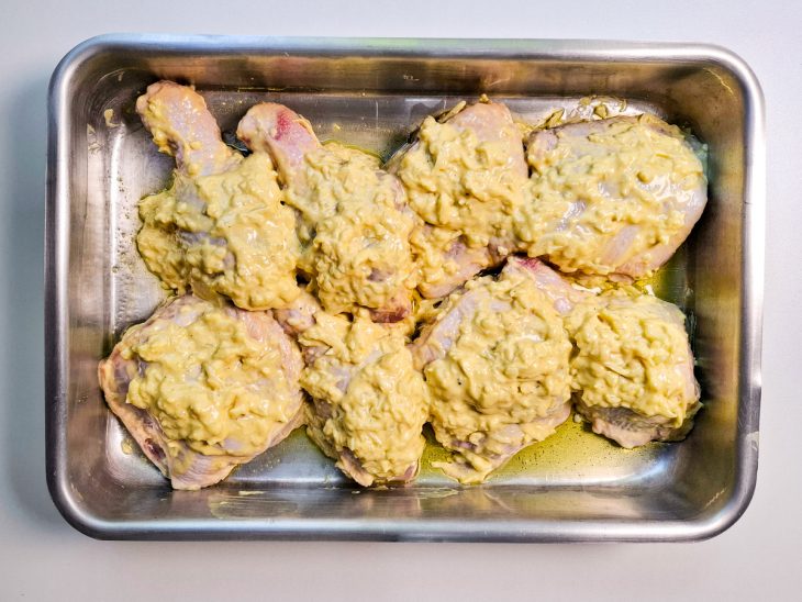 Pedaços do frango dispostos numa assadeira.