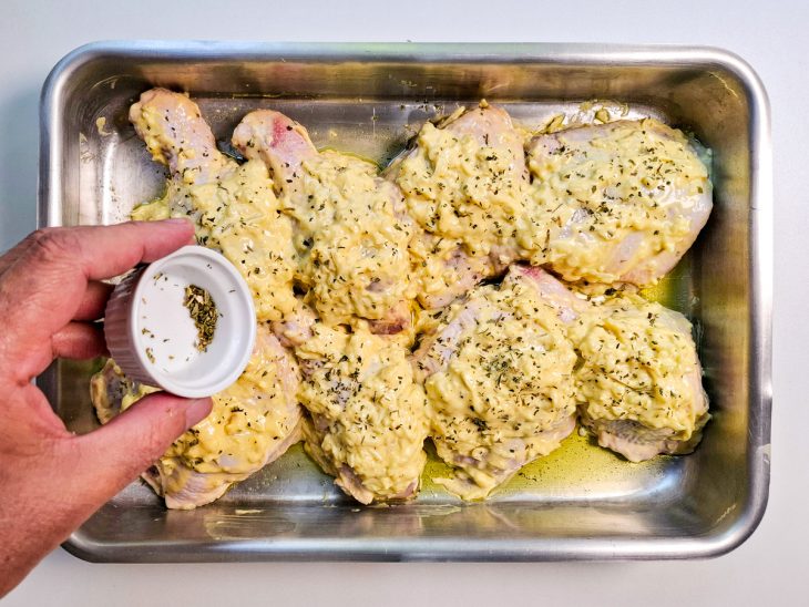 Na assadeira, orégano adicionado sobre o frango.