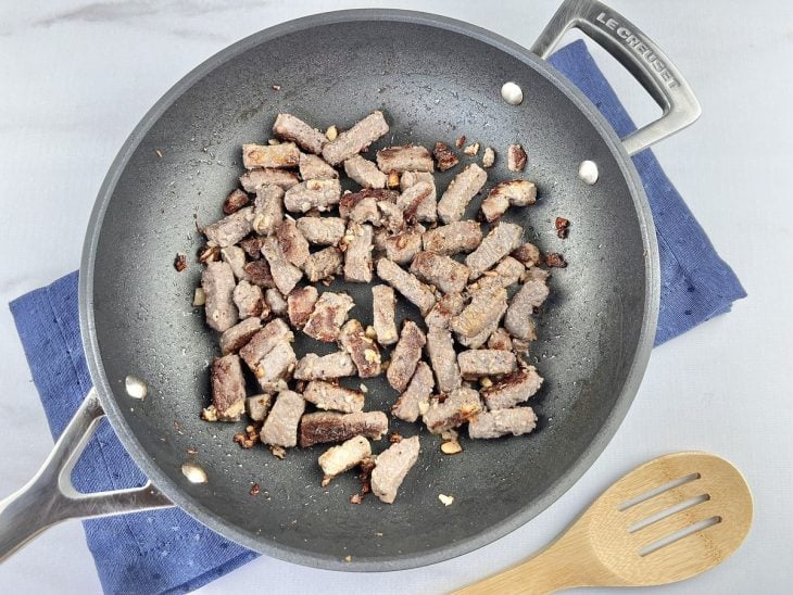 Cubos de carne fritando na frigideira.