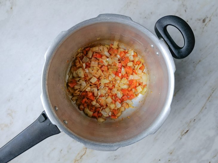 Tomate e temperos adicionados à panela formando a base do molho.