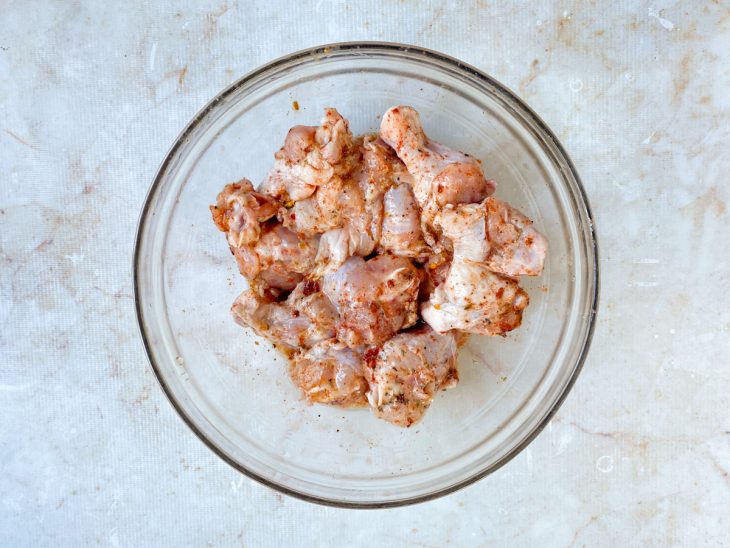 Coxinhas da asa temperadas num recipiente de vidro redondo.