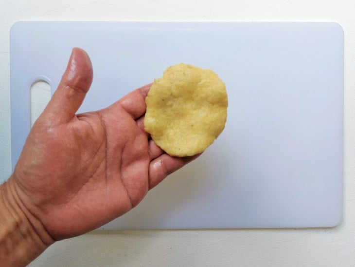 Uma porção da massa aberta em formato de disco em uma mão.