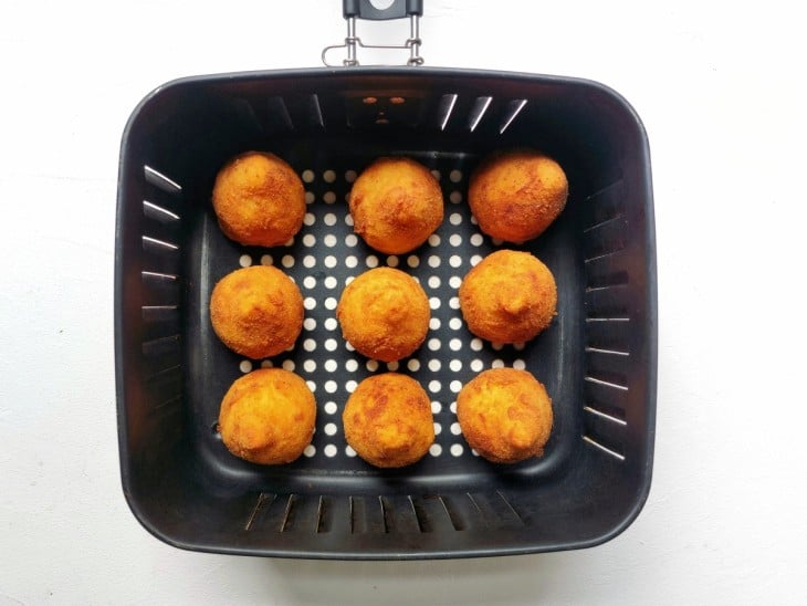 Airfryer com coxinhas assadas e com aspecto dourado.