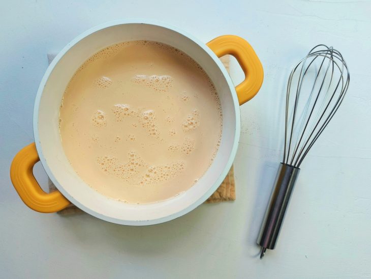 Uma panela contendo a mistura de leite condensado, creme de leite, amido de milho, leite, gemas e baunilha.