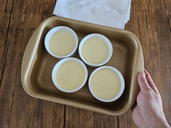 Creme despejados em ramequins colocados em uma travessa.