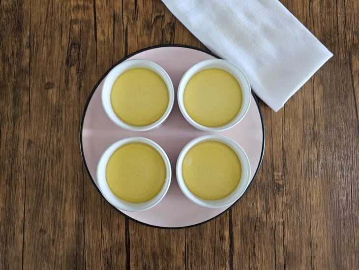4 ramequins de crème brûlée em cima de um prato.