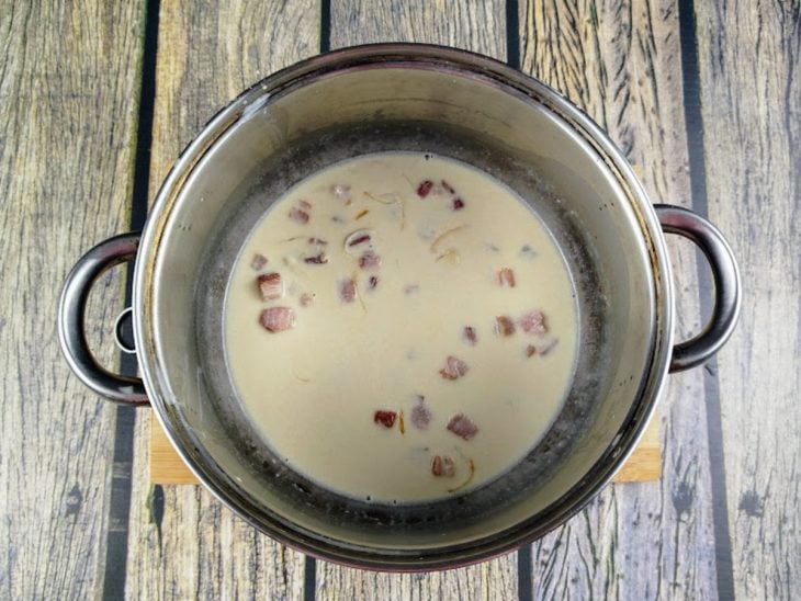Uma panela com o molho branco e o bacon.
