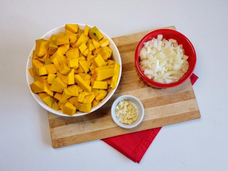 Recipientes com abóbora, alho e cebola picados.