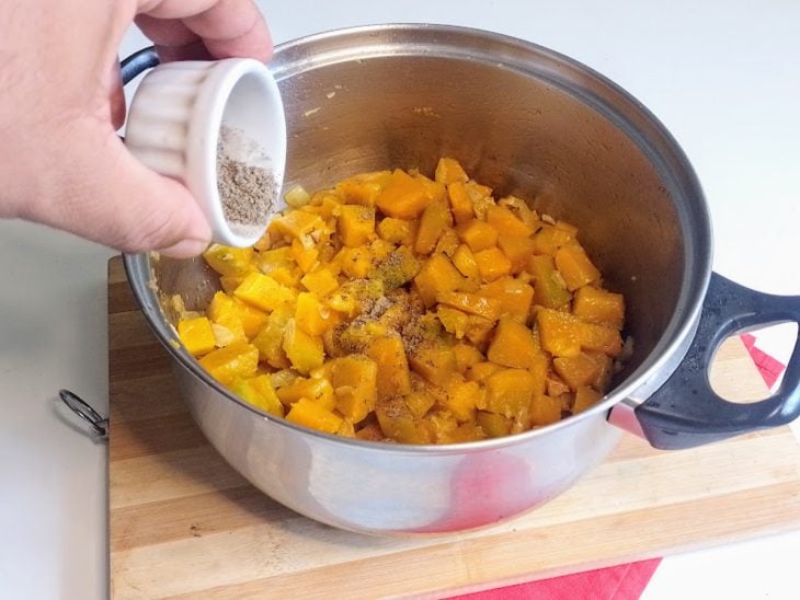 Uma panela com abóbora picada e temperos.