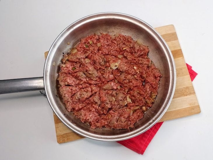 Uma frigideira com a carne moída e o tempero em processo de cozimento.