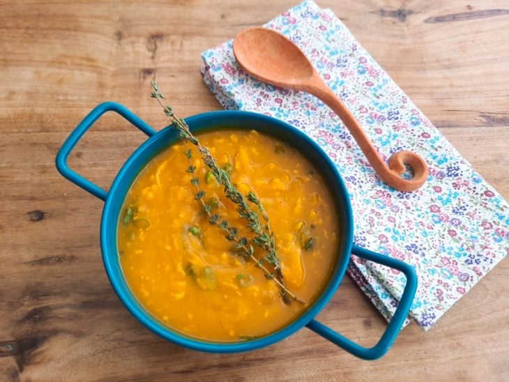Um recipiente contendo creme de abóbora com frango desfiado.