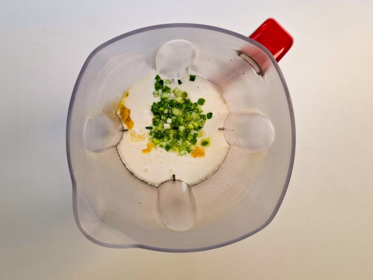 No liquidificador, o creme de leite, o alho, a cebolinha, o sal, e o suco de limão.