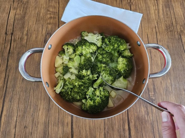 Uma panela contendo batata, brócolis e caldo de legumes.