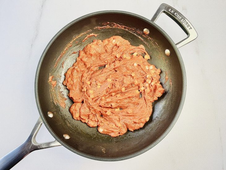 Manteiga, cebola, farinha de trigo e extrato de tomate misturados em uma frigideira.