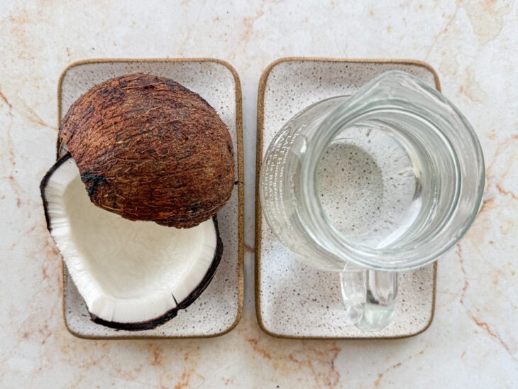 Ingredientes separados na bancada com coco fresco e água quente.