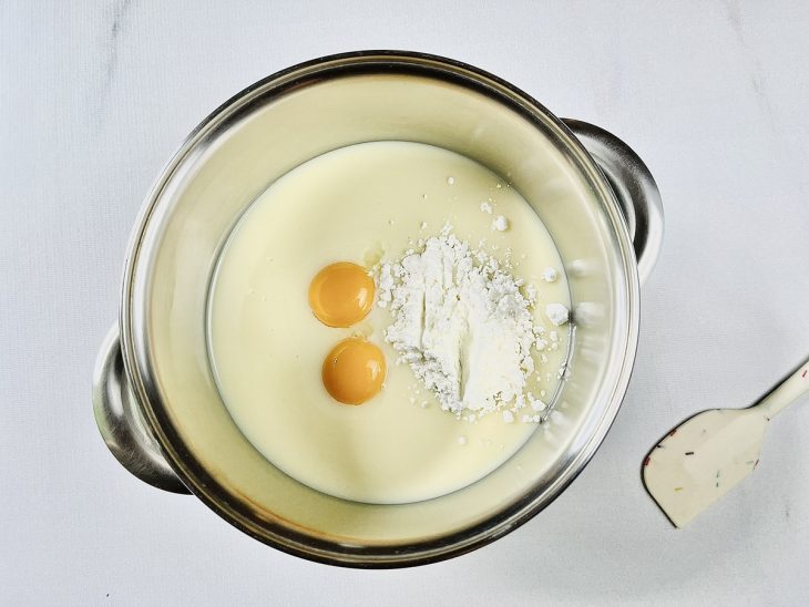 Numa panela, as gemas, o amido de milho e o leite condensado.