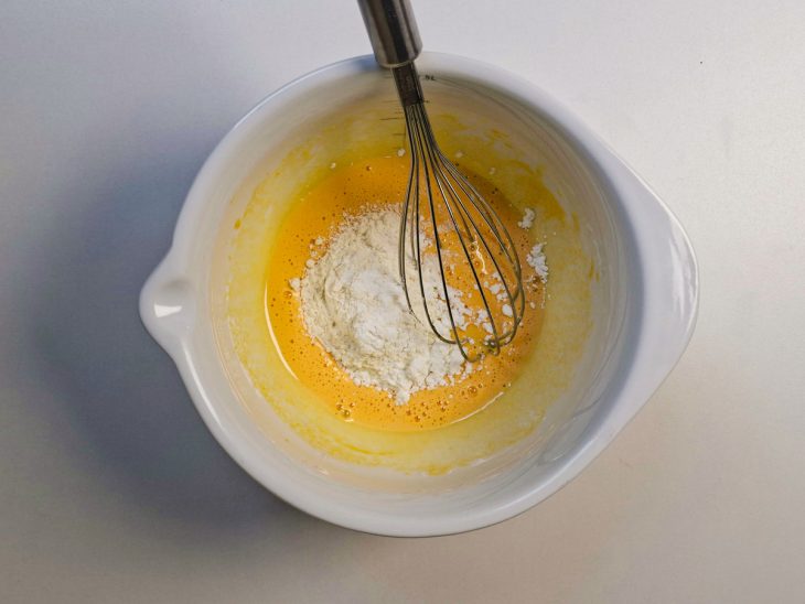 Mistura de ovos recebendo amido e farinha até ficar homogênea.