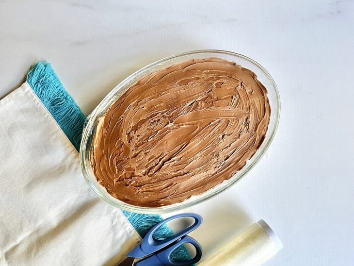 Um refratário contendo creme de cupuaçu com chocolate, coberto com plástico filme.