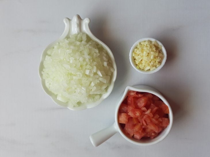 Recipientes com cebola, alho e tomate picados.