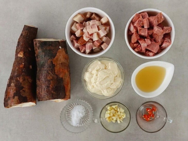 Ingredientes organizados na bancada, com bacon, linguiça, alho e pimenta-de-cheiro já picados em cubos pequenos.