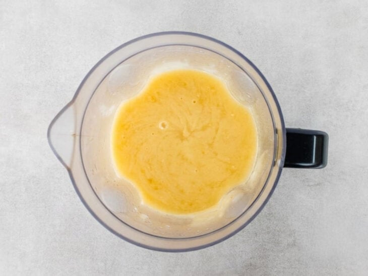 Mandioca cozida sendo batida no liquidificador até virar um creme liso e homogêneo.