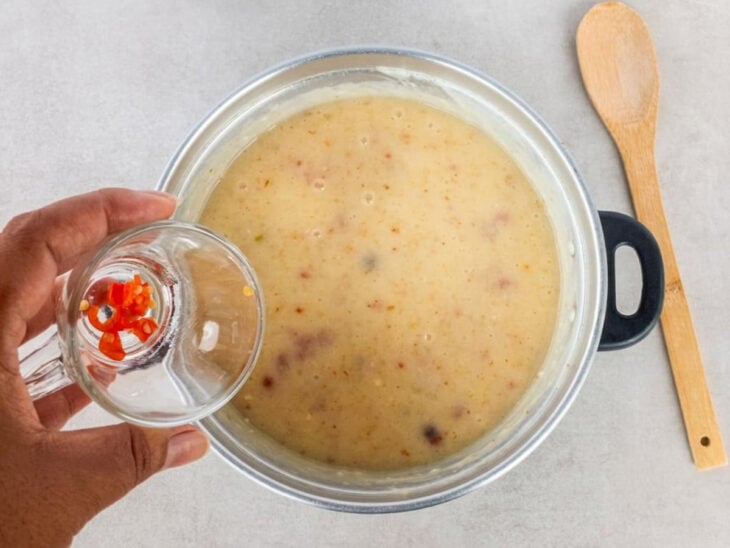 Requeijão cremoso sendo misturado ao creme e pimenta-de-cheiro adicionada no final do preparo.