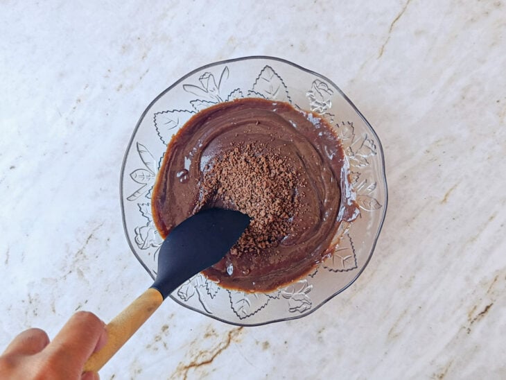 Segunda porção de Ovomaltine em flocos sendo adicionada ao creme já frio.