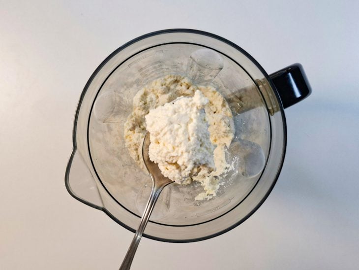 Colher com porção da mistura do liquidificador após adição de leite.