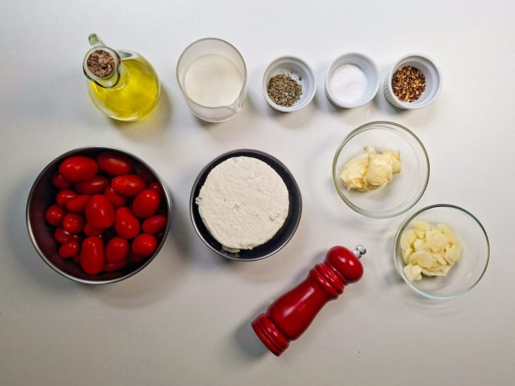 Ingredientes organizados sobre a bancada com alho sendo picado.