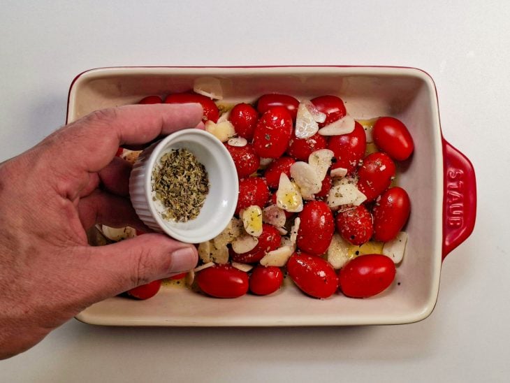 Refratário com tomates assando no forno até dourar.