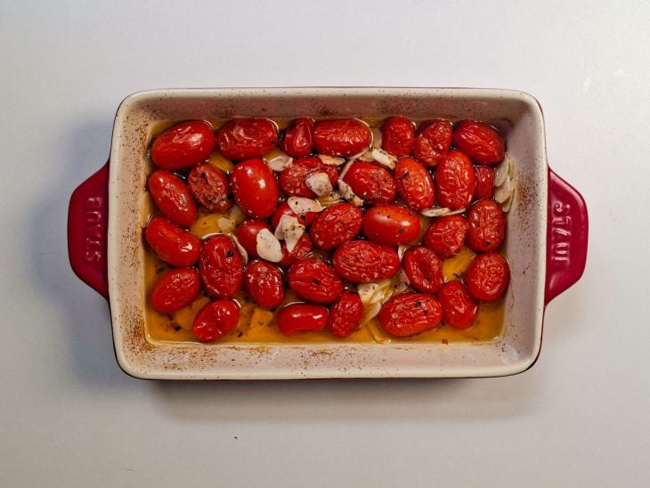 Tomates regados com azeite e orégano sendo misturados.
