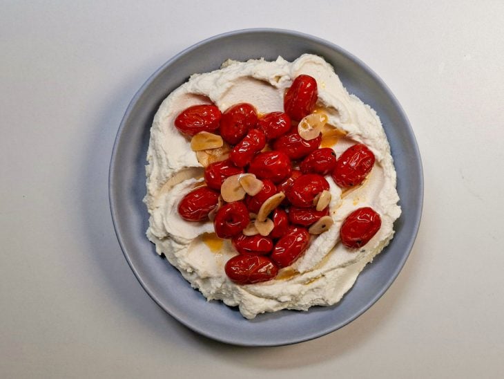 Tomates assados sendo distribuídos sobre o creme.
