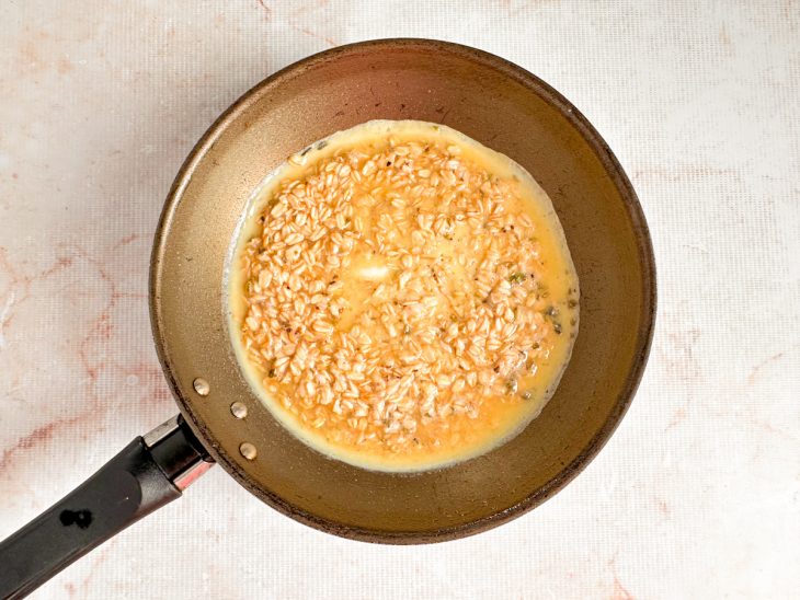 Massa de crepe de aveia sendo despejada em frigideira antiaderente levemente untada.