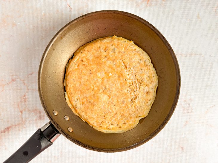 Crepe de aveia dourando em fogo médio-baixo na frigideira.
