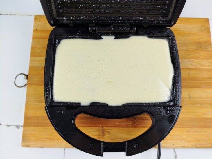 Uma sanduicheira com a massa do crepe.