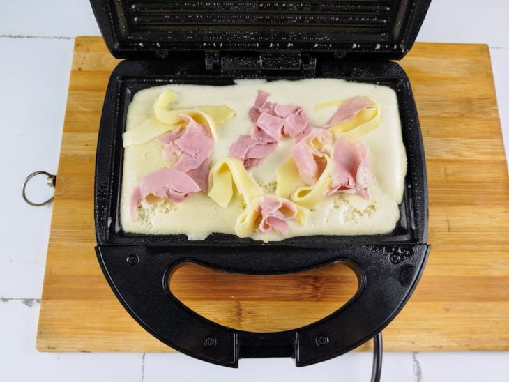 Uma sanduicheira com a massa do crepe e o recheio.