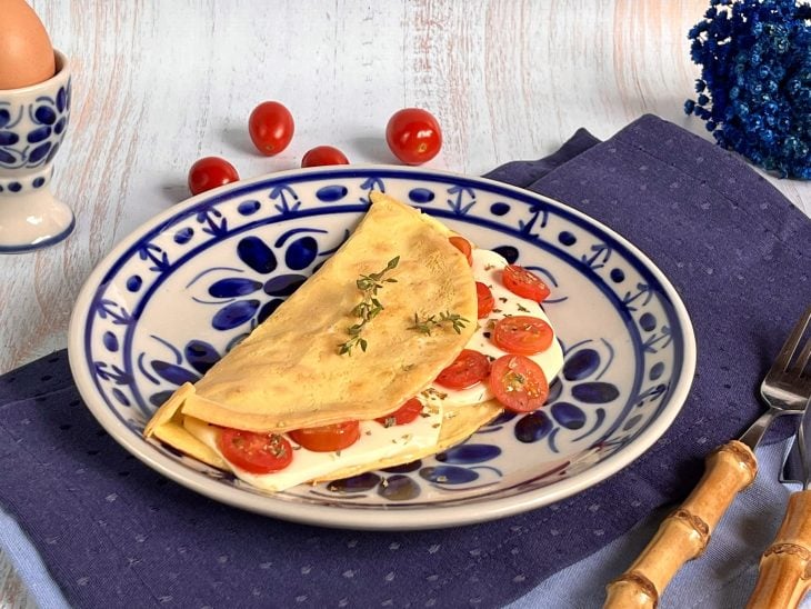 Um prato contendo uma crepioca de queijo com tomate e orégano.