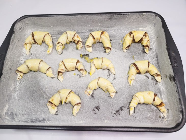 Uma forma untada contendo vários croissants crus de massa folhada.